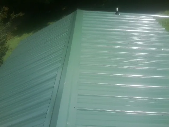 New green metal panels meeting at the ridge of a roof — Flat Roof Repair work by our crew in Warwick