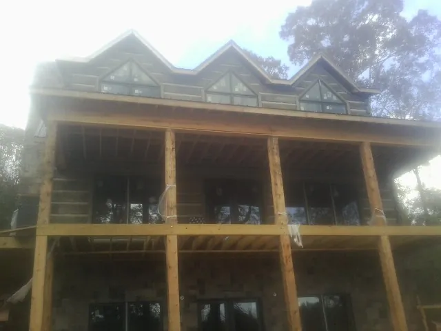 Dormers and porch framing on a large log home under construction — Roof Coating work by our crew in Warwick